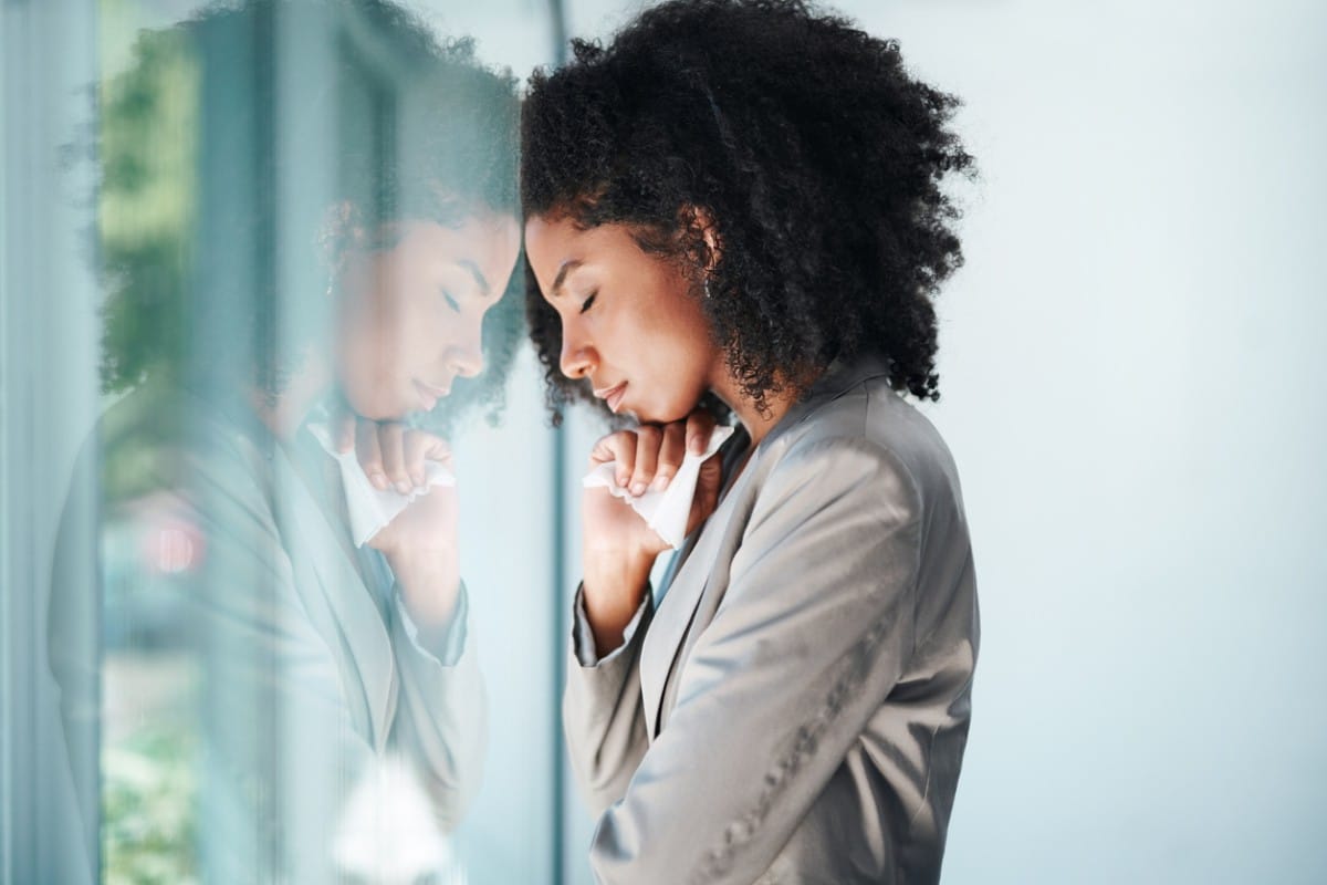 A woman leaning against a window appearing forlorn