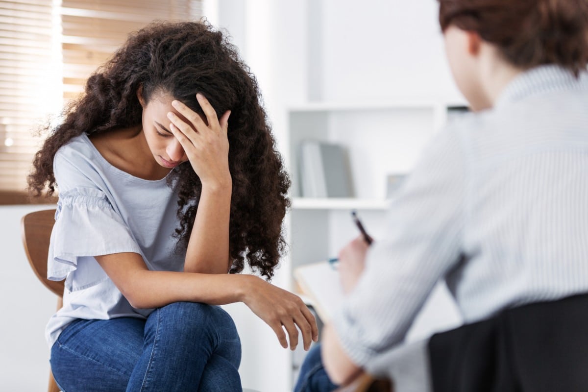 A woman holding her head while dealing with PTSD