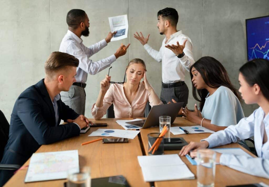 A woman appearing tired while others argue during a meeting