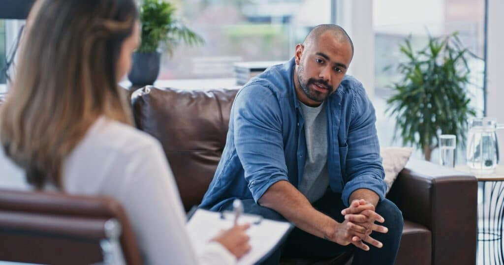 An adult man sitting on a couch engaging in acceptance and commitment therapy in Naperville