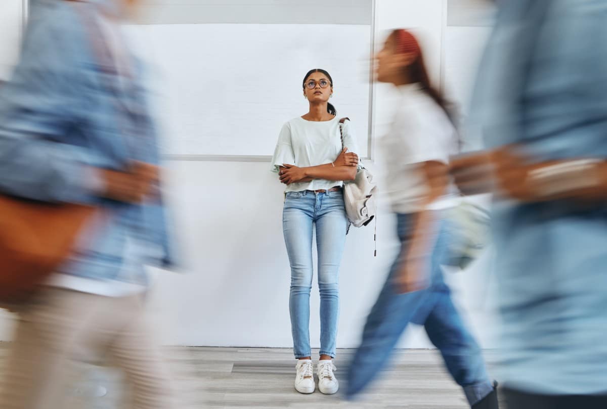 A woman struggling with anxiety standing outside as people rush by