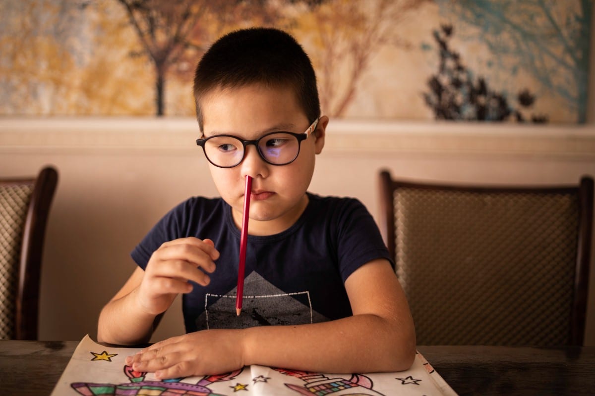 A boy with ADHD distracted with a pencil up his nose