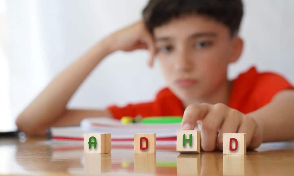 A boy organizing letter blocks to form the word ADHD