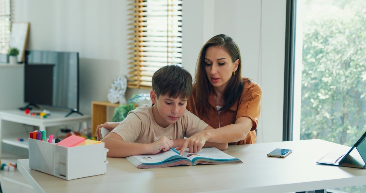 A woman helping a boy with a learning disability with homework