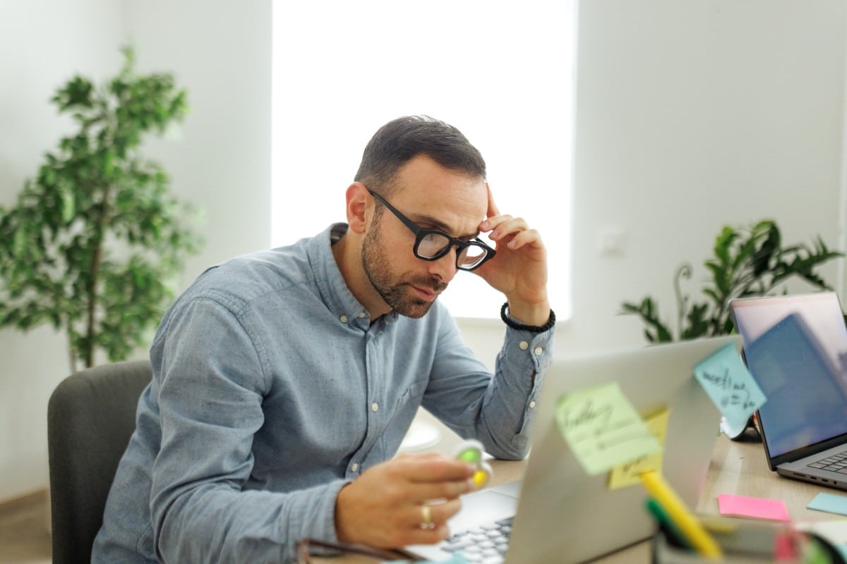 A man leaning over a laptop covered in sticky notes