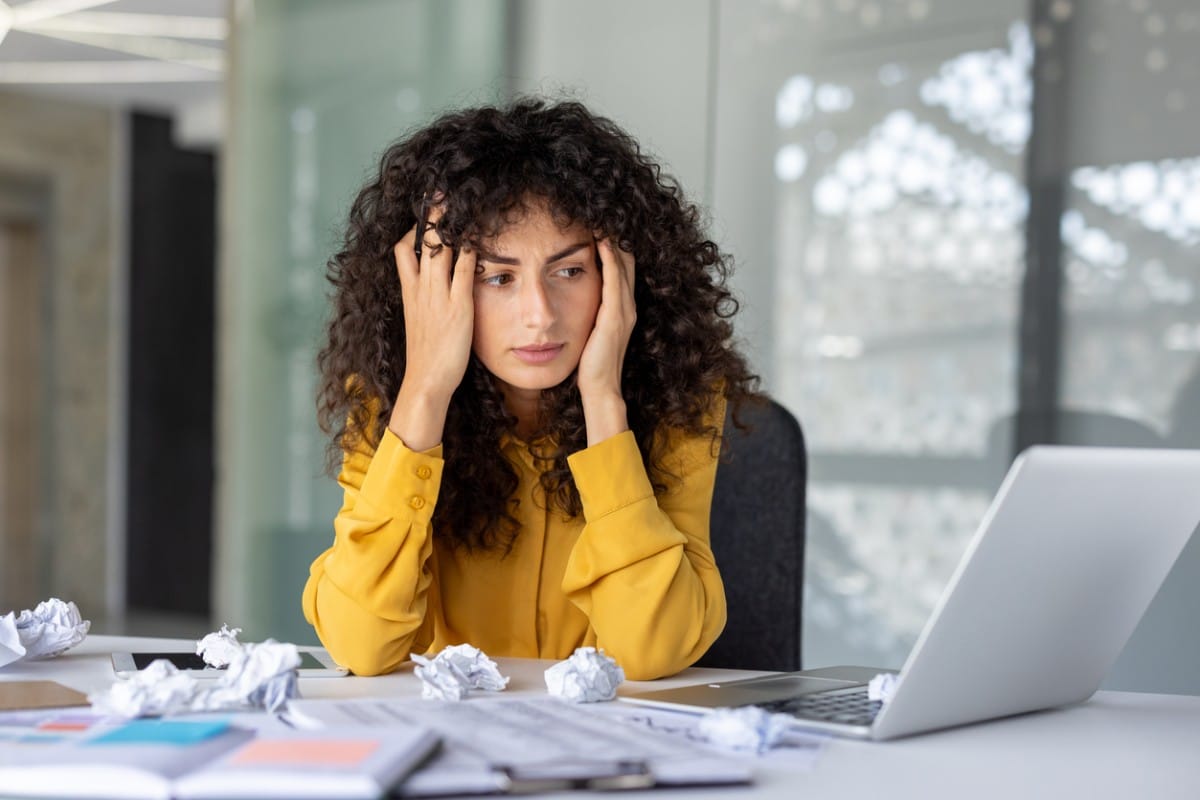 A woman looking tiredly at her laptop