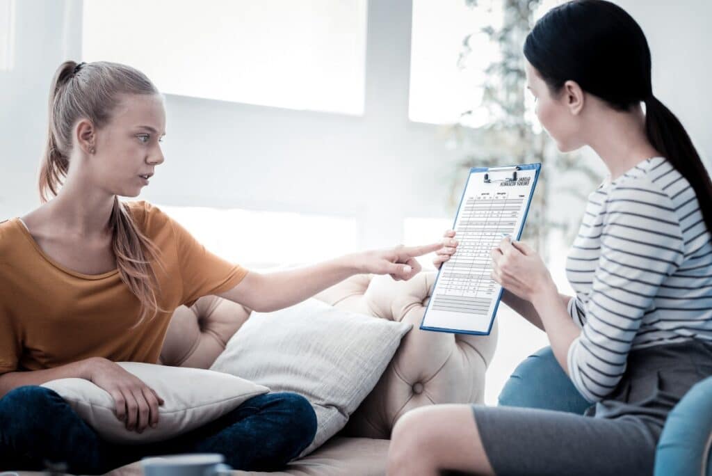 A teenage girl pointing at a document during a therapy session in Naperville